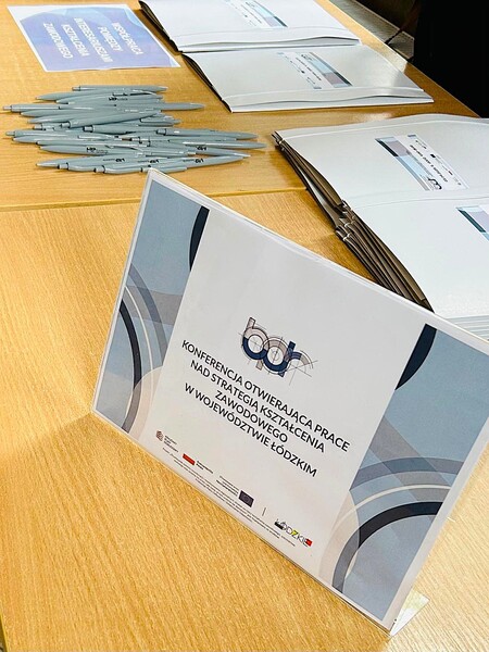 Na zdjęciu znajduje się clipboard  informujący o konferencji otwierającej prace nad Strategią Kształcenia Zawodowego w Województwie Łódzkim.