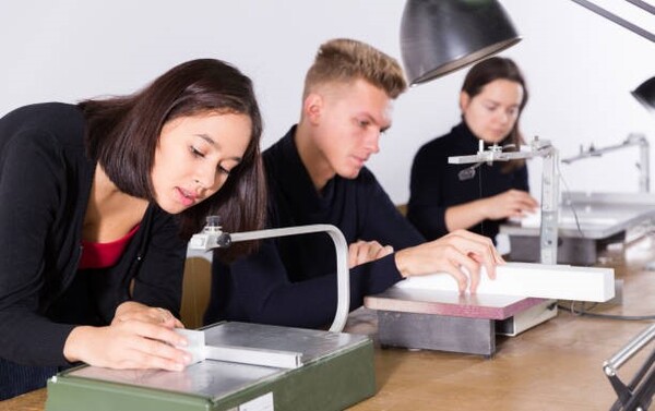 Na zdjęciu widzimy trzy osoby, dwie dziewczyny i chłopaka, wykonujące zadania techniczne.